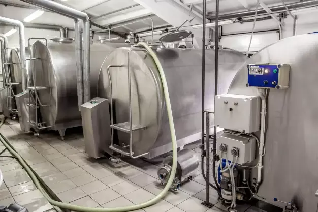 Tanques de resfriamento em aço inox com painéis elétricos em sala industrial